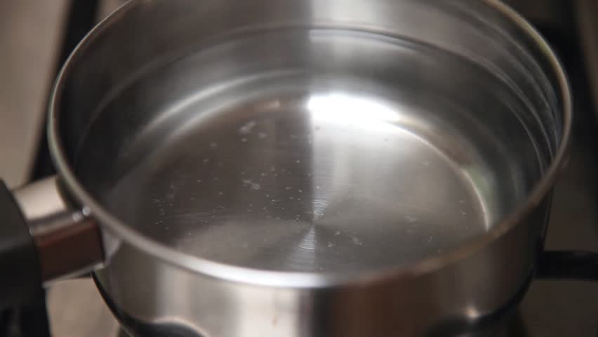 Steam of boiling water on stove in kitchen.