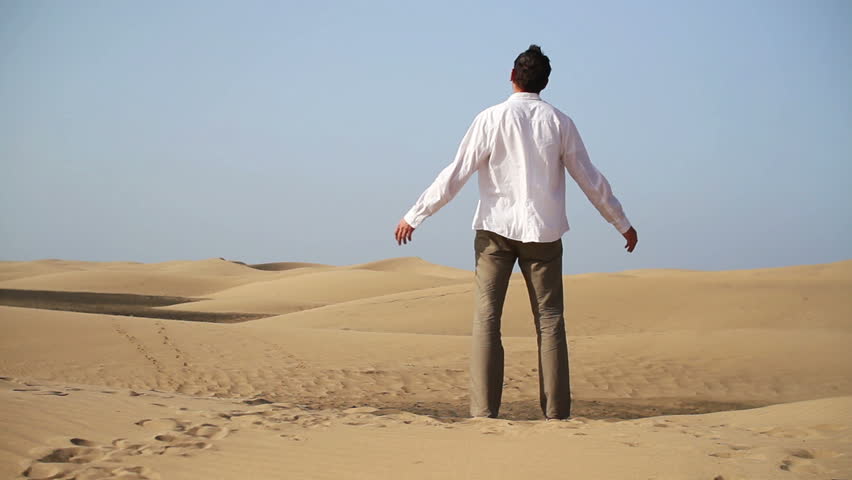 Man with wide open arms standing on the desert
