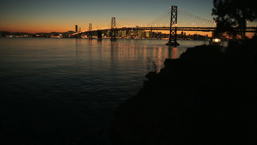 Aerial sunset time lapse view of the Oakland Bay bridge, Fishermans Wharf and the city skyscrapers of San Francisco,