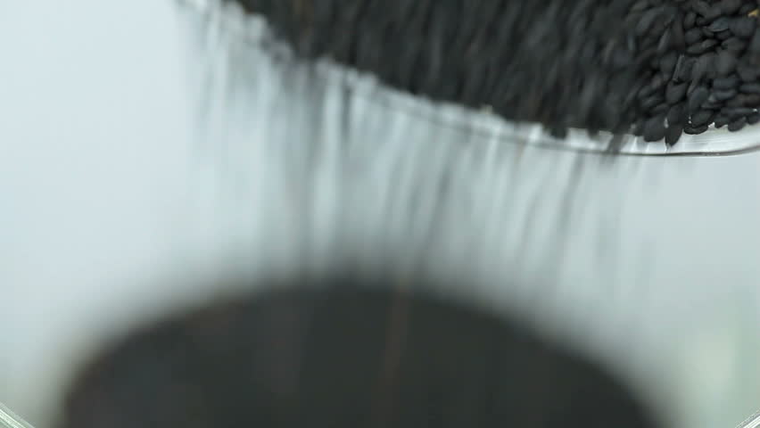 Pouring sesame seeds into a glass.