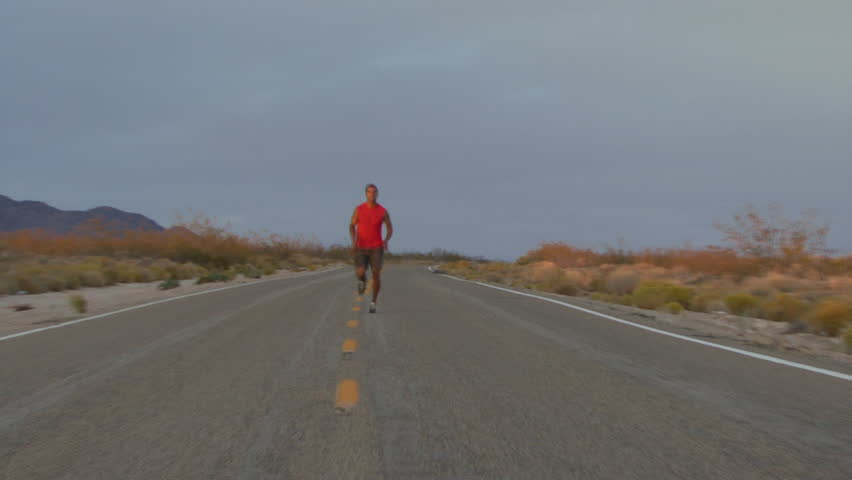 Male running along road at sunset