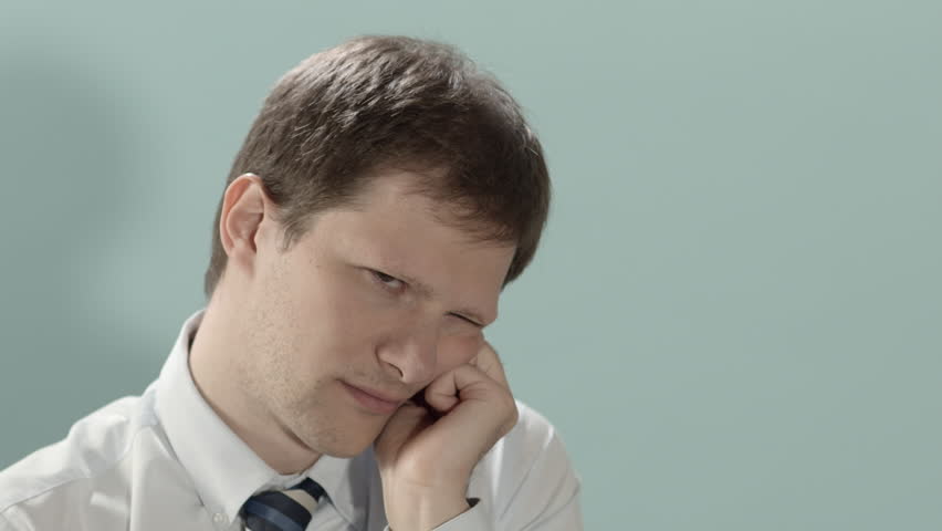 Bored mid adult businessman yawning at work against blue background. Copy space