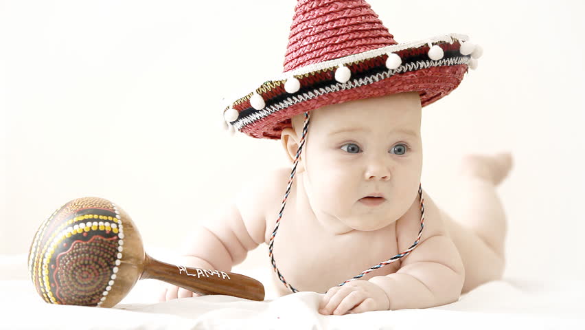 Baby in sombrero hat with maracas on the light background