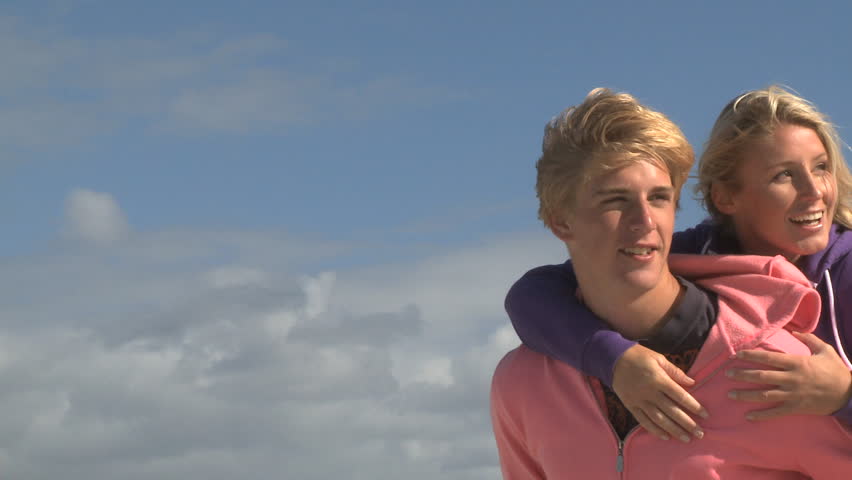 MEDIUM SHOT OF A YOUNG MAN GIVING A YOUNG WOMAN A PIGGYBACK