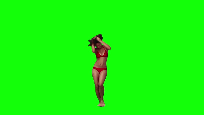 A woman wearing a red bikini is dancing against a green background