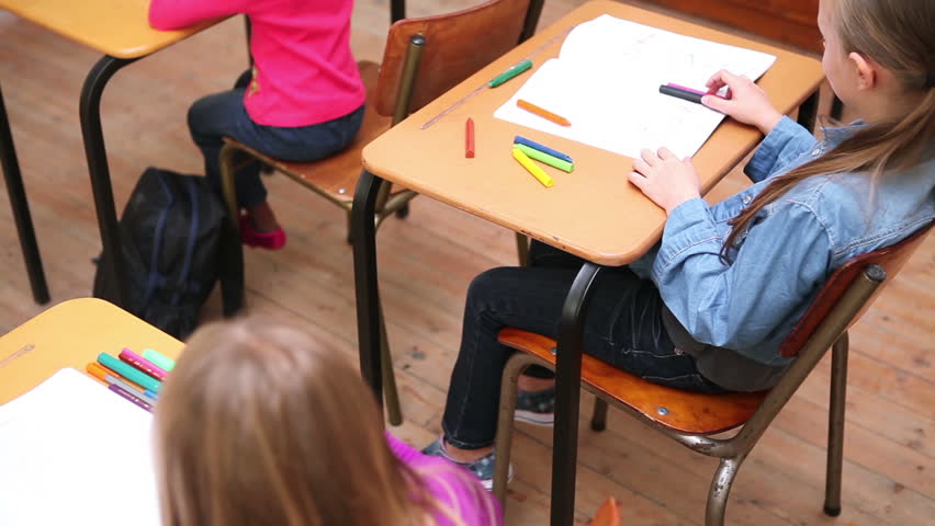 Cute pupils whispering secrets in the classroom