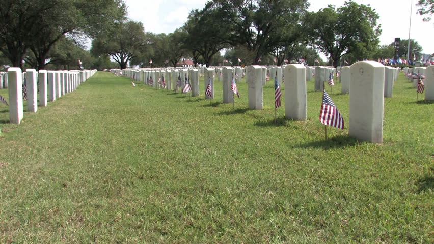 Graves and headstones at Ft Sam Houston Veterans Cemetery San Antonio Texas. Headstones and flags. Heroes and warriors, members of military and veterans. Pan right.