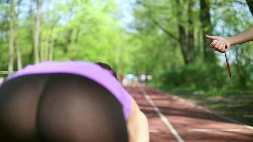 Women running on the track, trainer checking their time, slow motion, dolly shot
