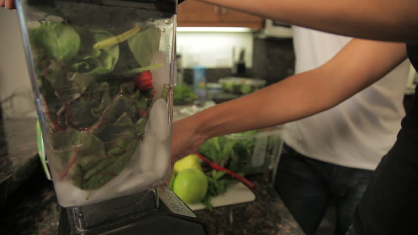 person mixing veggies with ice in blender