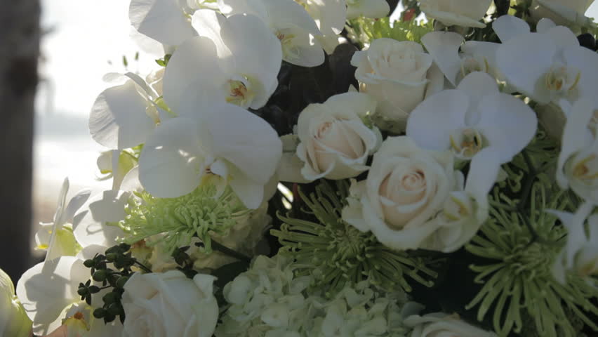 A panning close up of a wedding floral arrangement with ocean in the background