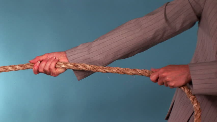A woman pulling on a rope and a man who comes to assist her.
