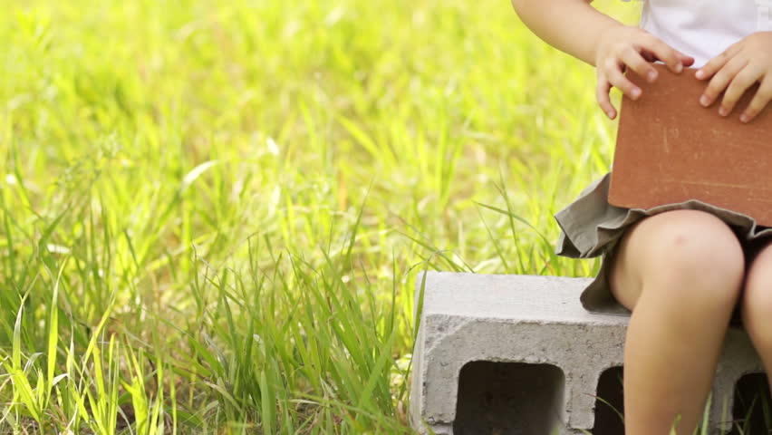 Girl in hard hat sitting on cinder block gives thumbs up