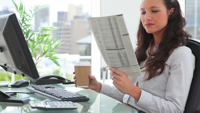 Businesswoman reading a newspaper in an office