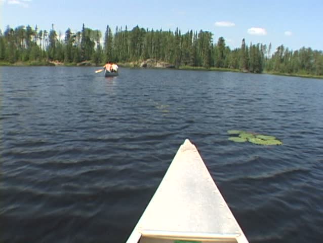 Point of view while riding inside aluminum canoe at lake in the Minnesota Boundary Waters following two people in canoe. More clips available in series.