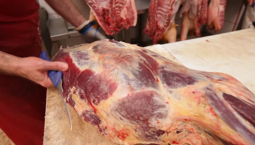 Butcher shop - original camera raw files. Butchers cut and trim beef, veil and pork carcasses.