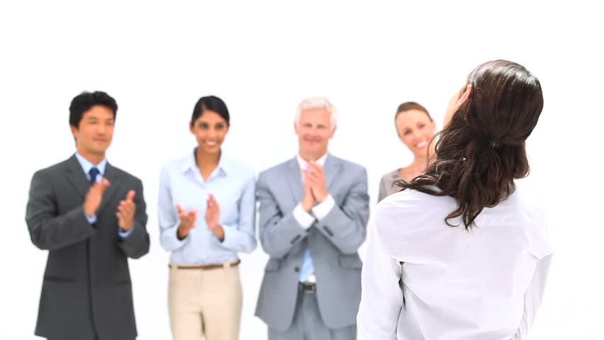 Brunette being applauded by her co-workers against a white background