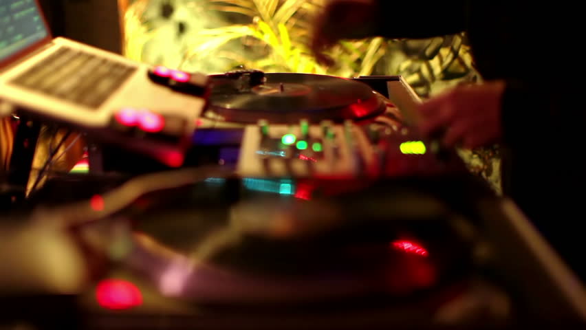 cool dj behind the turntables performing in a bar