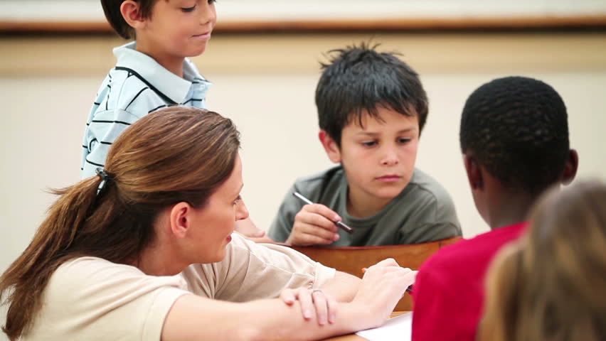 Teacher talking with her pupils in the classroom