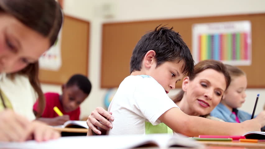 Teacher explaining something to a pupil in the classroom