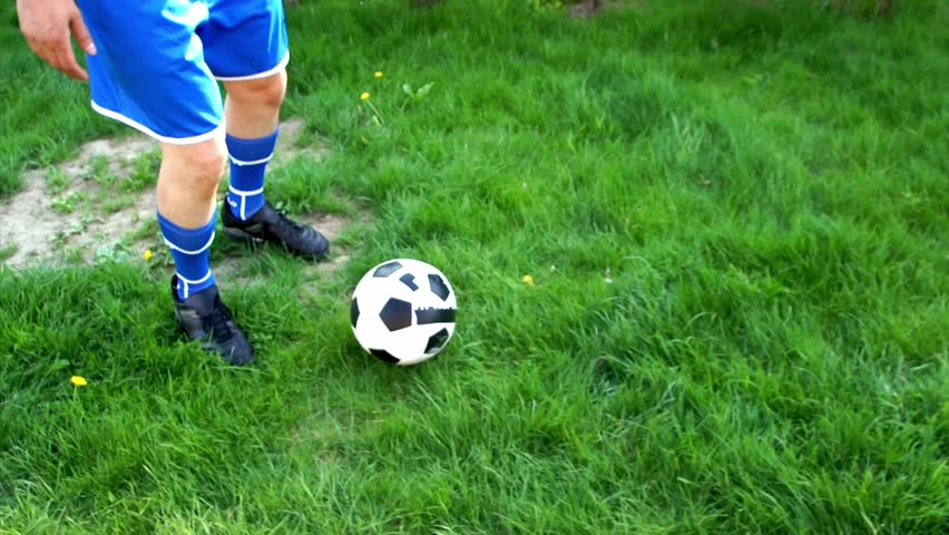 Football player running with ball and shooting, slow motion