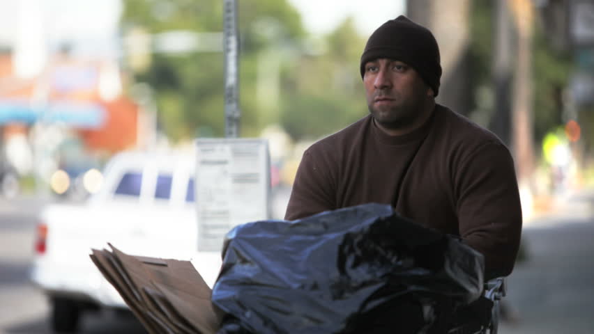 Homeless person pushing his shopping cart down the street