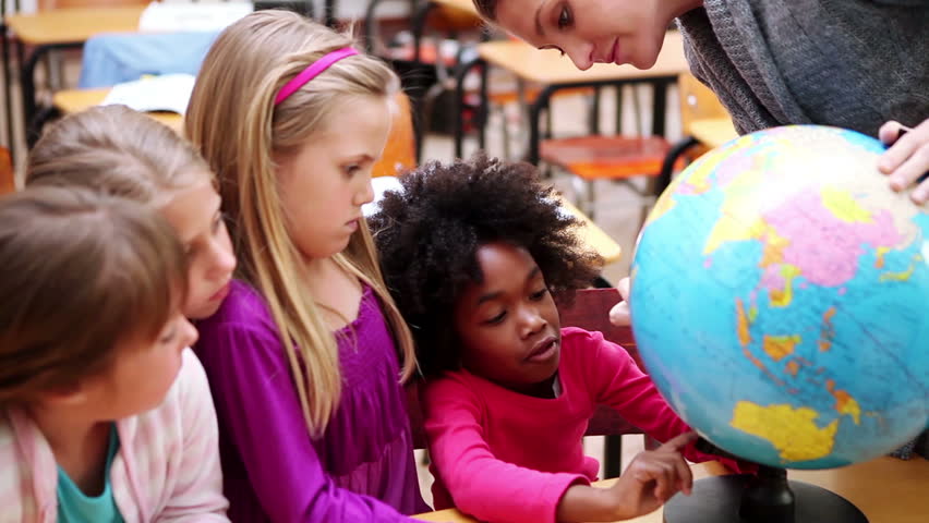 Happy pupils looking at a globe in the classroom
