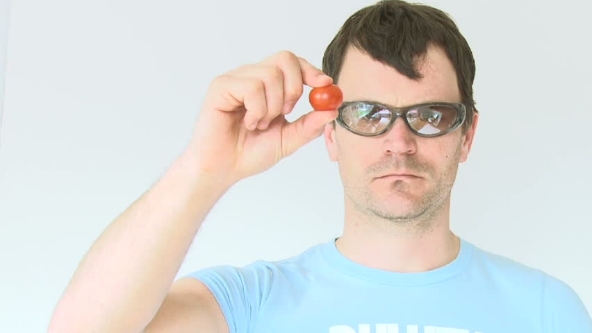 Funny tough guy squeezes small tomato which squirts him in the eye.