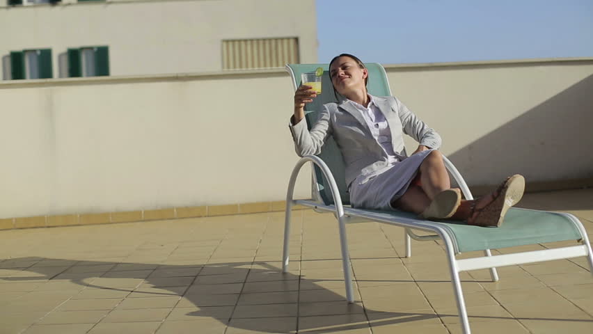 Happy businesswoman with drinks relaxing on sunbed
