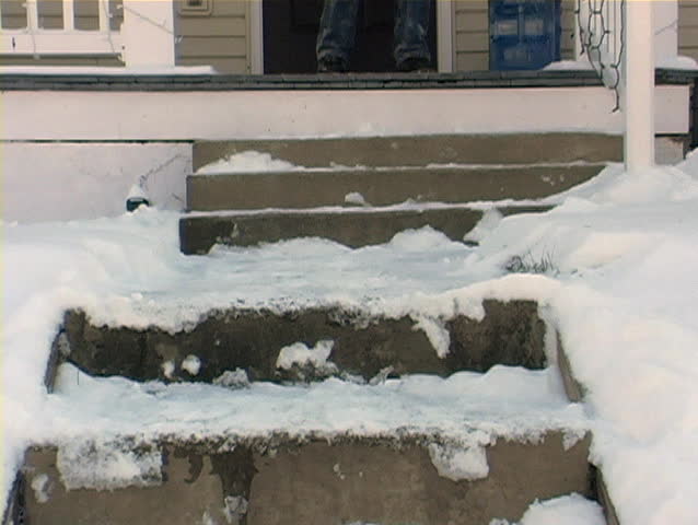 Sprinkling salt on a sidewalk full of snow.
