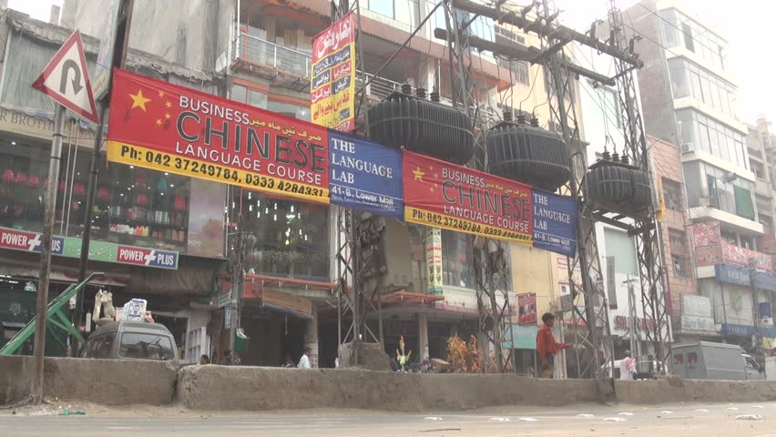 LAHORE - 18 OCTOBER 2010: Motorbikes, rickshaws, lorries and other traffic pass a banner promoting Chinese language learning in the Pakistani city of Lahore