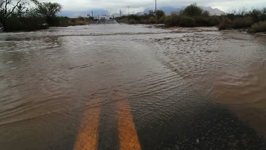 Water swirls over yellow line, floods road after heavy monsoon storm, low, wide angle. 1080p