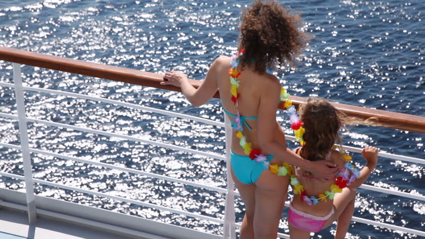 Mother and daughter stand on ship deck in beautiful color garland from flowers