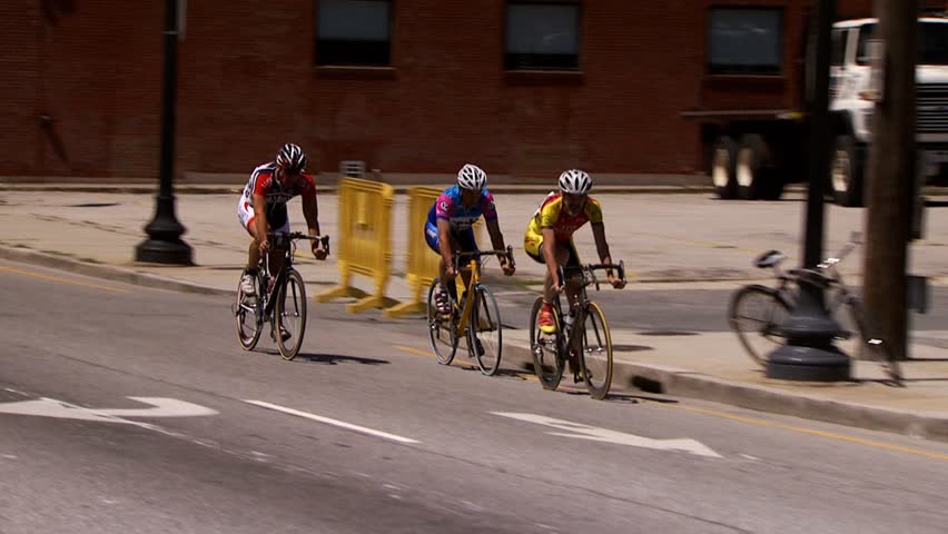 PROVIDENCE, RHODE ISLAND - SEPTEMBER 3, 2009: Three men rounding street corner in bicycle race in city - slow motion