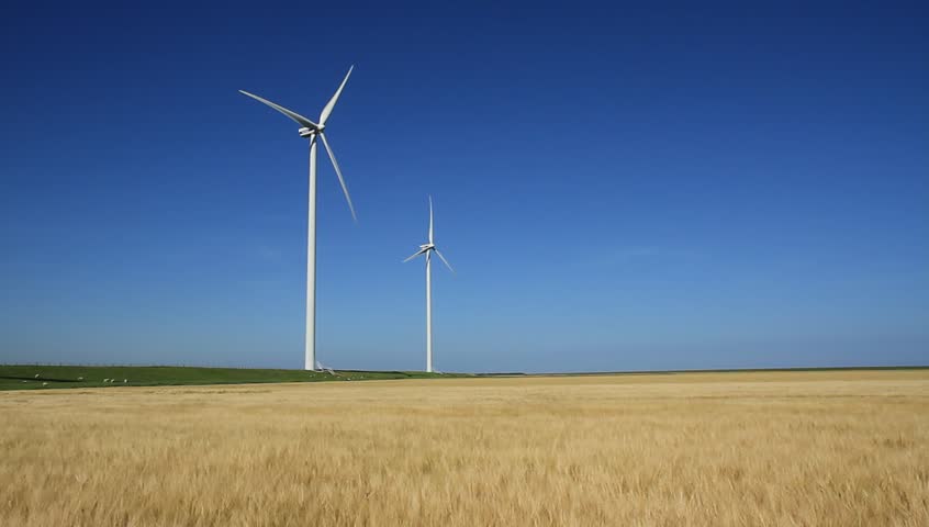 Two modern wind turbines generating sustainable energy in a field with wheat.