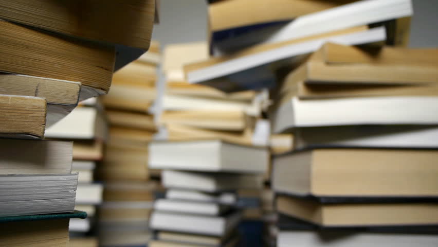 Camera tracks through teetering piles of books.