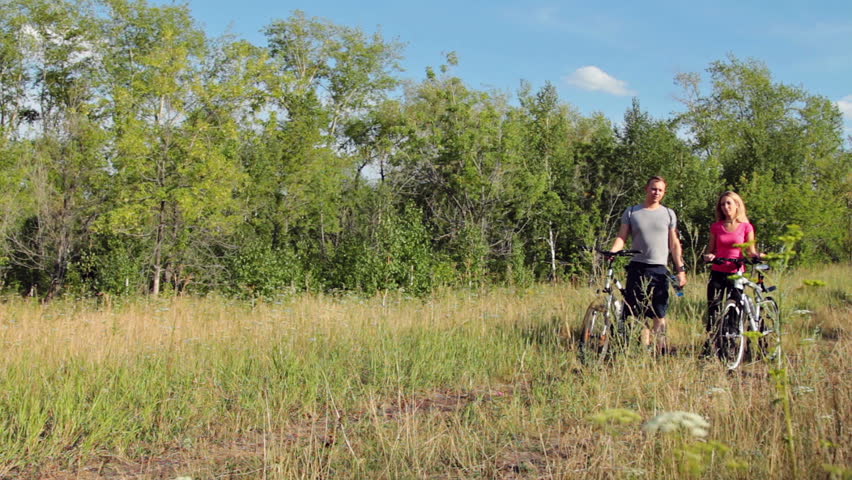Attractive couple refreshing after biking in the forest