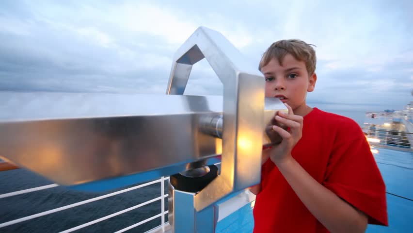 boy looks in stationary field-glass afar from ship deck close up