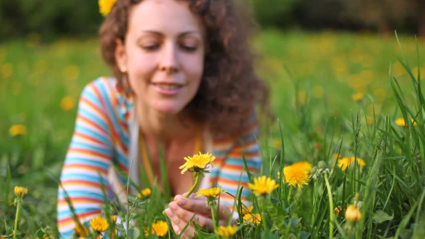 Young woman holds dandelion which water from plastic bottle