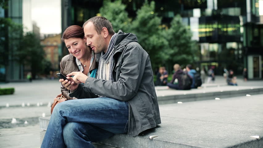 Happy couple with smartphone in the city
