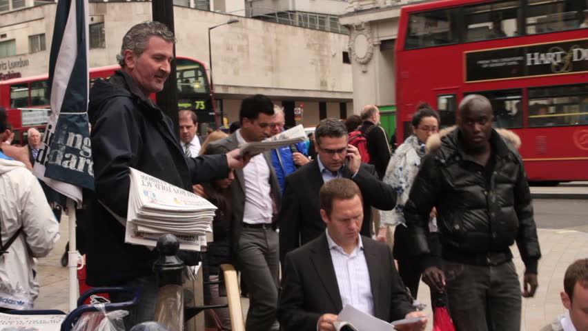 LONDON - MAY 14: Unidentified newspaper man distributes the free daily Evening Standard newspaper to unidentified commuters entering Oxford Circus underground station on May 14, 2012 in London.