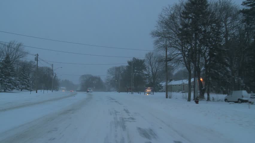 NEW ENGLAND - CIRCA NOVEMBER 2009: View through windshield while driving on snowy street at dusk 