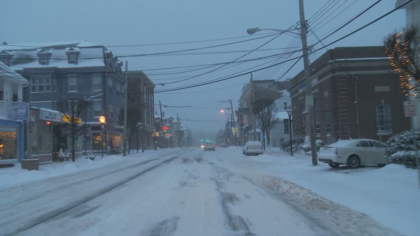 NEW ENGLAND - CIRCA NOVEMBER 2009: View through windshield while driving on snowy street at dusk 
