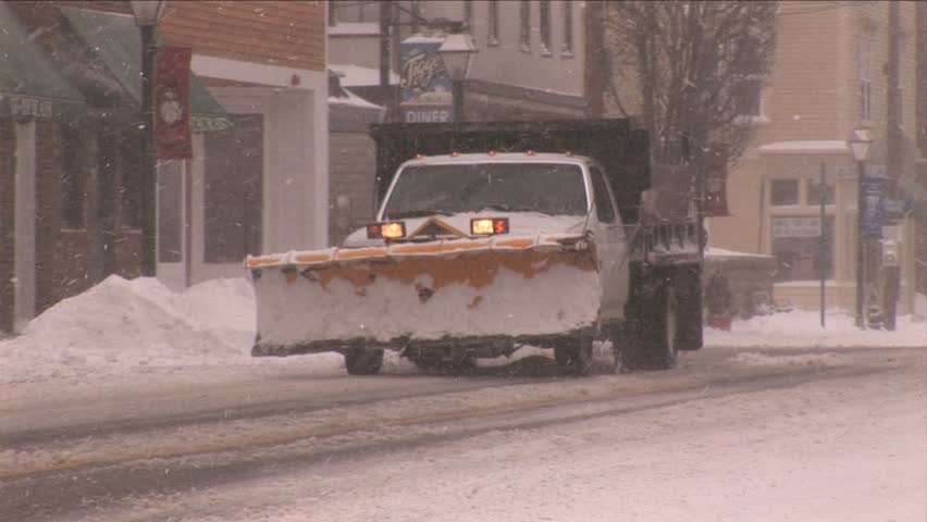 NEW ENGLAND - CIRCA JANUARY 2006: Snow plow driving down snowy downtown street