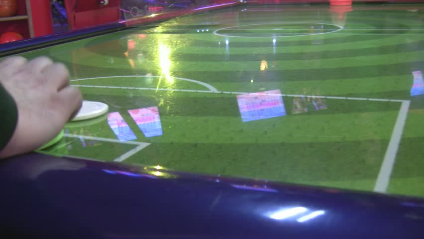 Two young persons playing against each other table game air hockey in a club