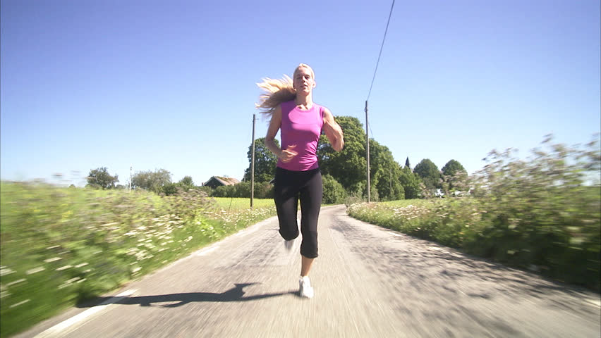 A woman jogging next to a corn field