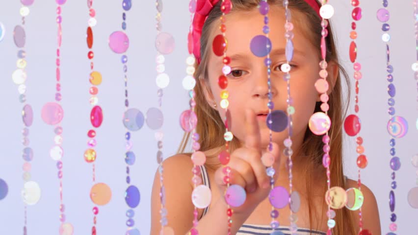 girl behind curtain from threads with multi-colored round plates counts them showing on everyone finger