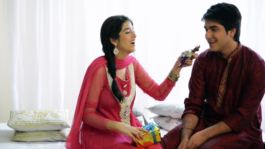 Locked-on shot of a teenage girl feeding chocolate to her brother