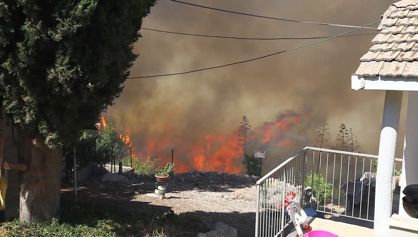 TIVON, ISRAEL - AUGUST 09: A man tries to save his home from burning after a forest fire breaks out in Kiryat Tivon. Rescue workers struggle to prevent further damage. Tivon, Israel August 09, 2012