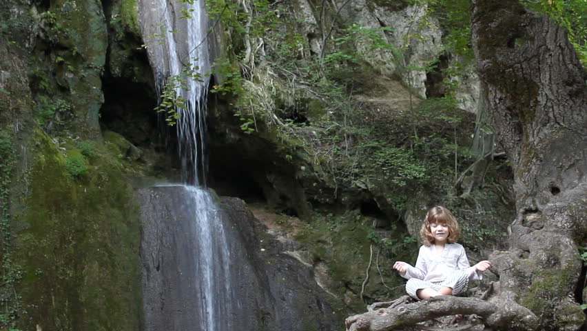 little girl meditate by the waterfall