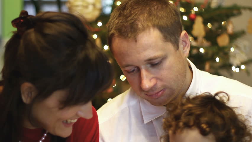 Happy family sitting at couch with christmas gifts
